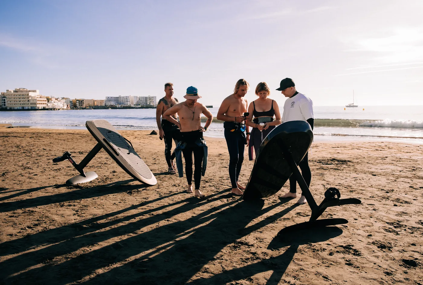 Un instructor explica el equipo de eFoil a un grupo en la playa